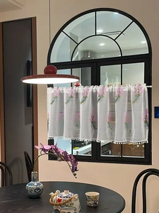 Detail of white semi-sheer cafe curtain with lavender embroidery and pom-pom trim