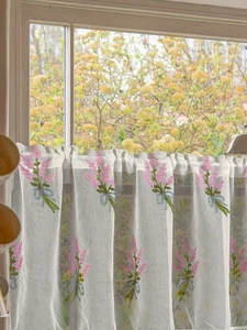 Detail of pink flower embroidery and rod pocket header on a white sheer cafe curtain