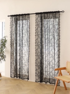 Detail of black lace curtain with elegant floral hollow patterns and scalloped edges