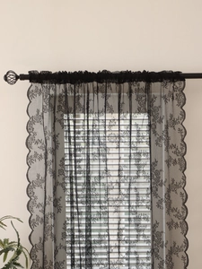 Close-up of black floral lace curtain with delicate scalloped edges and mesh texture