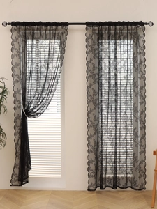 Detail of black lace curtain featuring delicate floral embroidery and scalloped edges