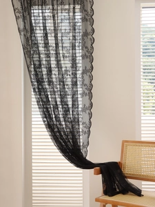 Close-up of black floral lace curtain showing intricate hollow patterns and scalloped edges