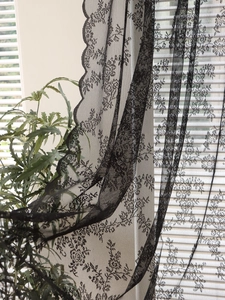 Detail of black lace curtain with floral patterns and scalloped edges for home decor