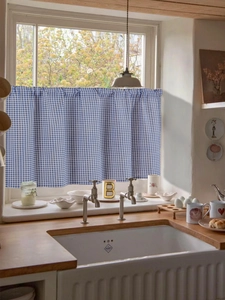 Close-up of blue and white gingham cafe curtain in a cozy kitchen window setting