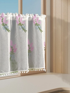 Detail of floral embroidery on lavender fabric curtain with white pom-pom trim