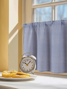 Close-up of blue and white gingham cafe curtain with rod pocket design in sunlit kitchen