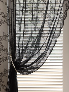 Detail of black lace sheer curtain with floral patterns and scalloped wave edges