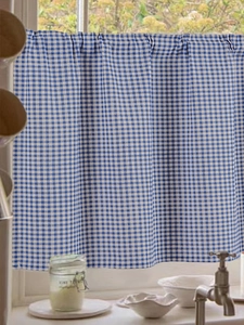Close-up of blue and white gingham cafe curtain with soft pleats on a kitchen window