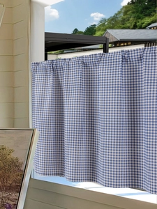 Close-up of blue and white checkered fabric curtain with elegant pleated top detail
