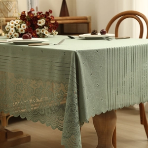 Elegant light green lace tablecloth with floral hollow embroidery on a wooden dining table