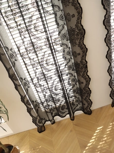 Detail of black lace window curtain with vintage floral patterns and scalloped edges