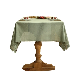 Light green striped tablecloth with hollow lace edges on a wooden table, rustic style