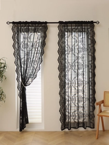 Detail of black floral lace curtains featuring intricate vintage embroidery and wavy edges