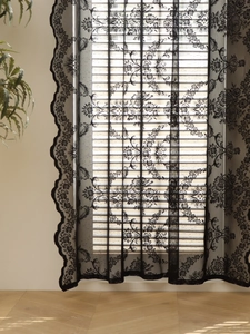 Close-up of black lace curtain with classic floral patterns and elegant scalloped edges