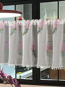 Detail of sheer cafe curtain with pink floral embroidery and white pom-pom trim