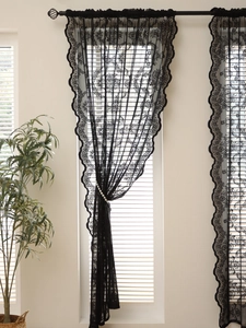 Detail of black lace curtain with floral patterns and pearl tieback for windows