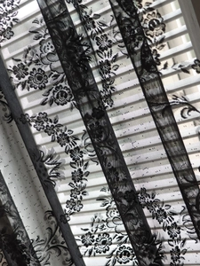 Detail of vintage French black floral lace curtain with intricate rose embroidery patterns
