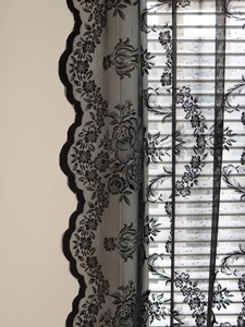 Detailed close-up of vintage black floral lace curtain with elegant scalloped edges