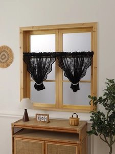 Detail of black lace cafe curtains with floral texture and elegant pearl tiebacks