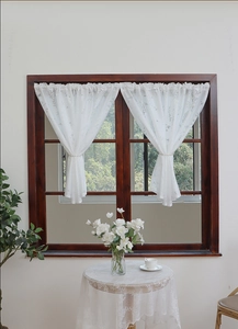 Close-up of white lace curtain with lavender embroidery tied on a wooden window