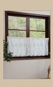 Detailed close-up of a white lace cafe curtain with lavender leaf print in sunlight