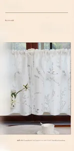 Detail of white lace cafe curtain featuring intricate grey leaf woven patterns in vintage style
