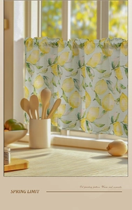 Detail of yellow lemon oil painting print on a small kitchen curtain in soft sunlight