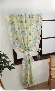 Detail of yellow lemon print curtain with white pleated lace trim on light green fabric