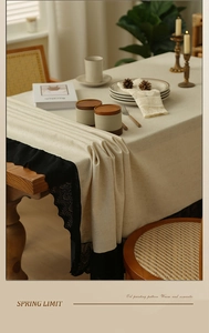 Detail of beige cotton linen tablecloth featuring exquisite black lace trim and texture