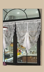 Close-up of white lace kitchen curtain with floral patterns and delicate ribbon tie