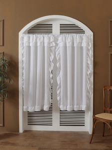 Detailed close-up of white sheer cafe curtains with ruffled edges on a small window