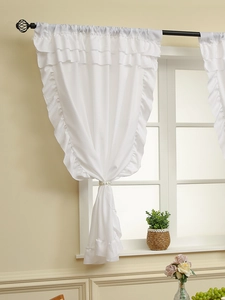 Detail of white multi-layered ruffle sheer curtain with decorative beaded tieback