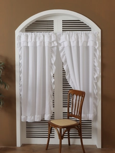 Detail of white ruffled sheer curtains with multiple layered pleats for a French vintage look