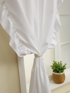 Detailed texture of white ruffle curtain with elegant pearl buckle clip detail