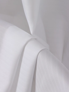 Macro shot of white sheer curtain fabric showing fine twill weave and soft texture details
