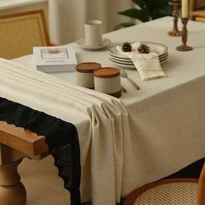 Vintage linen tablecloth with black lace edges on wooden dining table in home setting