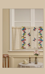 Detail of colorful butterfly embroidery on a beige translucent cafe curtain