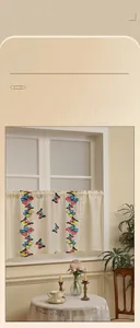 Detailed embroidery of colorful butterflies and delicate lace edges on beige cafe curtains