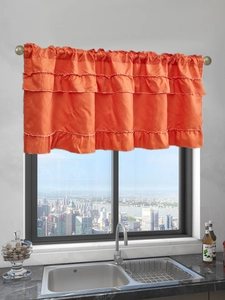 Macro detail of three-layer orange valance with ruffle edges and textured fabric