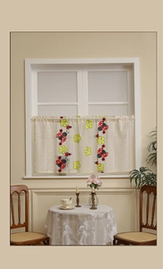 Detail of cafe curtain with ladybug and floral print hanging on white wooden window