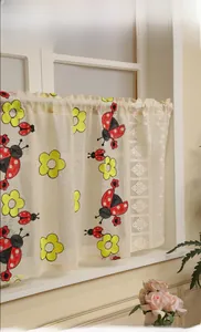 Detail of ladybug and yellow flower embroidery on cream lace cafe curtain