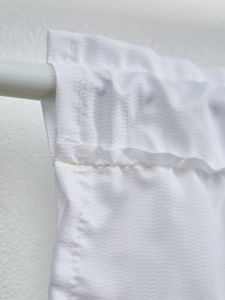 Detail of white cafe curtain with subtle twill texture and rod pocket design
