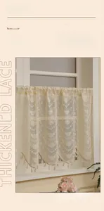 Dettaglio di tenda corta in pizzo crema con motivo floreale e nappe decorative