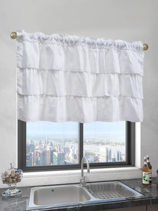 Close-up of white tiered cafe curtain with ruffled edges hung over a kitchen sink