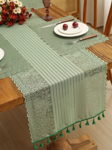 Detailed sage green lace table runner with floral hollow patterns and tassel fringe edge