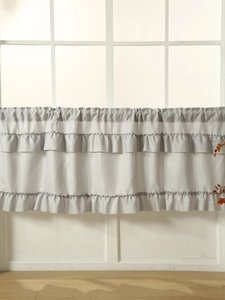 Detail of grey ruffled cafe curtain with tiered layers on a white grid window