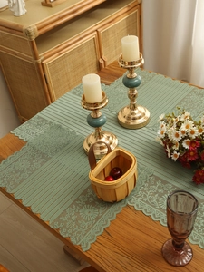 Close-up of light green hollow lace table runner with floral patterns and scalloped edges