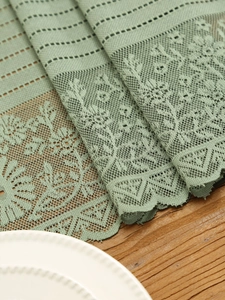 Detailed macro of Morandi green lace table runner with hollow floral jacquard and scalloped edges