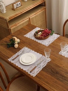 Macro detail of white vintage lace table runner with floral hollow patterns on wood table
