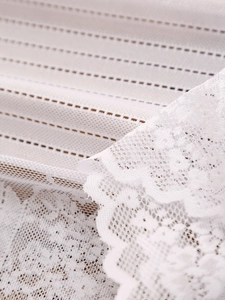 Close-up of white vintage lace runner featuring delicate hollow floral patterns and tassels